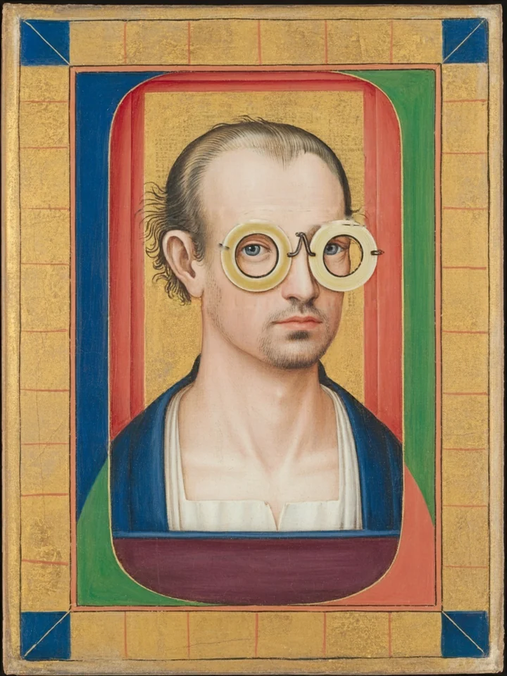 Justin Hartfield painted as a 15th-century miniature: a bust in a dark blue gown, wearing round riveted horn spectacles, on gold leaf in a gold frame